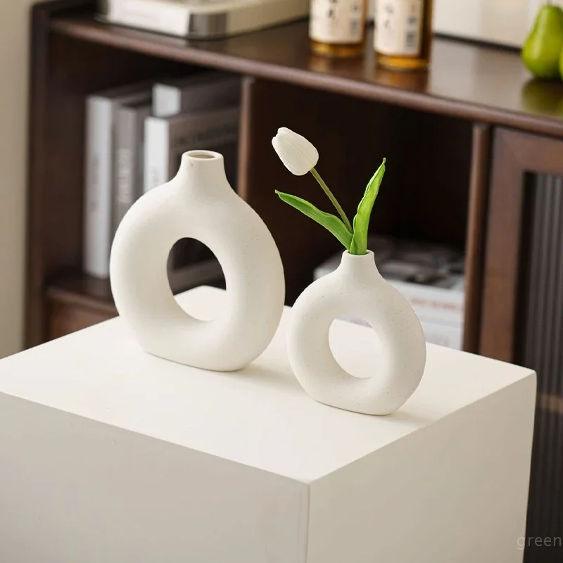 Vase décoratif blanc à la forme épurée sur une étagère de salon moderne