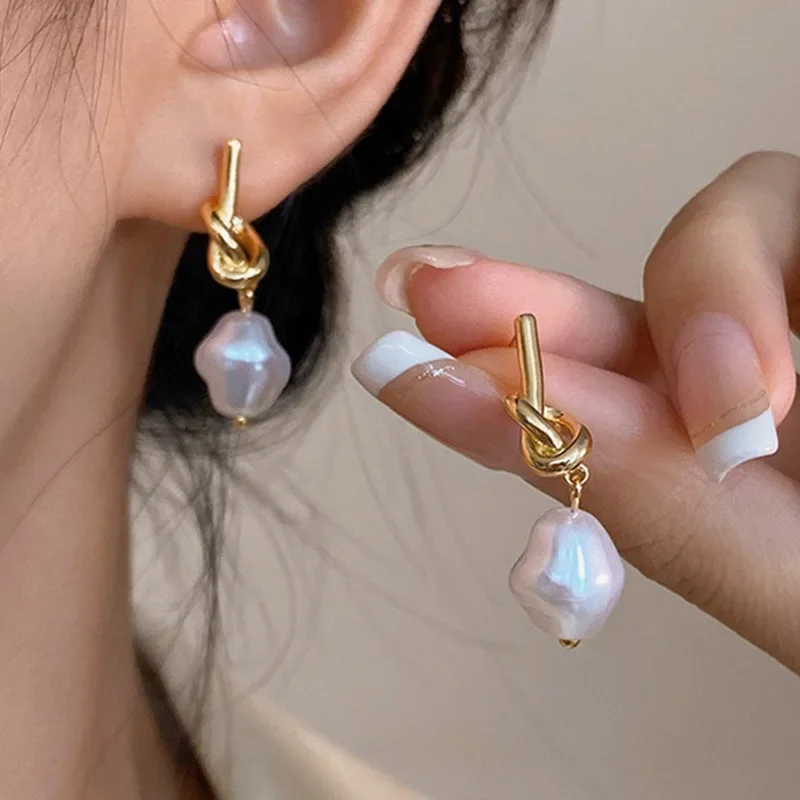 Modèle portant des boucles d'oreilles perles et doré avec une tenue élégante