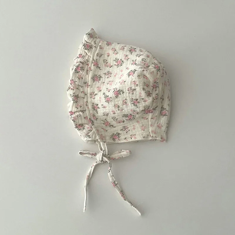 Gros plan d'un bébé portant un chapeau à fleurs, visage joyeux