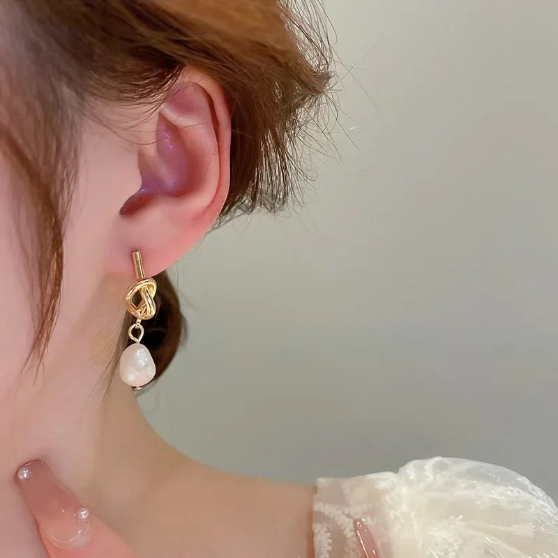Vue rapprochée des boucles d'oreilles montrant leur finition dorée et leurs perles